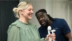 Woman doing a grip strength test while a Health Assessment Specialist looks on